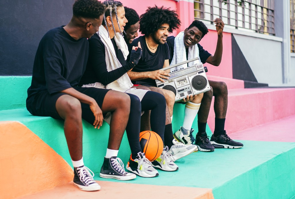 Group of friends laughing together on colorful steps after playing basketball